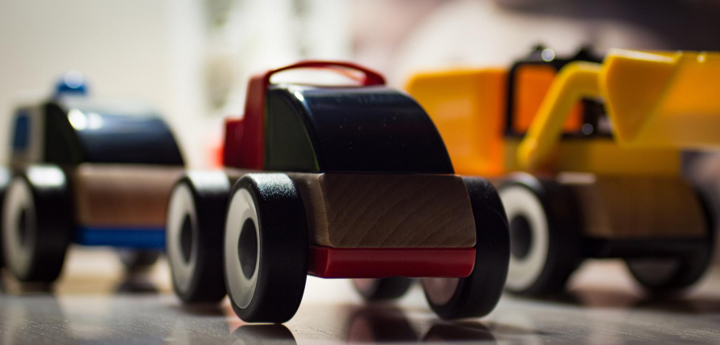 Two wooden toy cars and a yellow toy digger