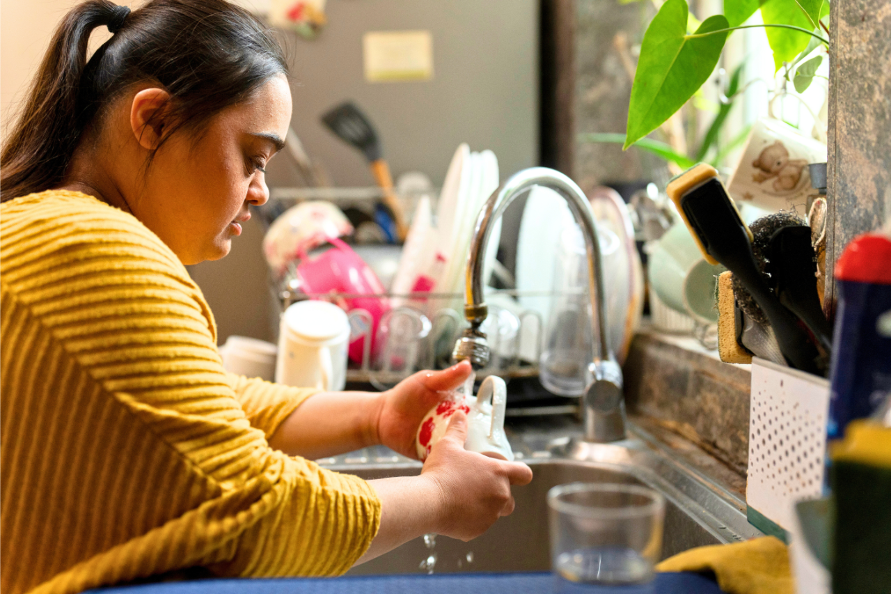 Young Woman With Downs Syndrome Washing Dishes