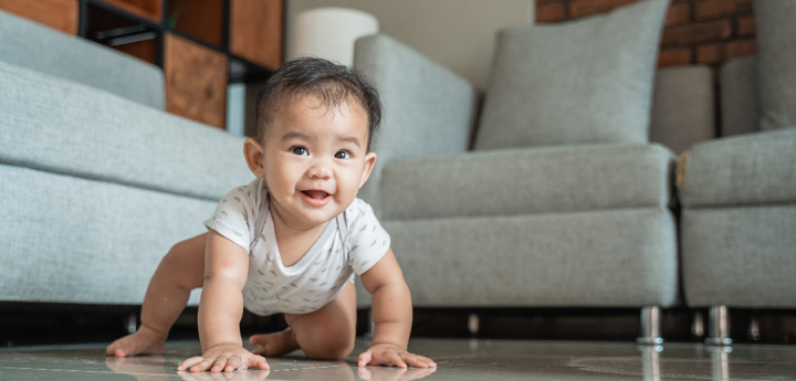 Baby crawling on floor in a living room.