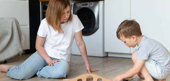 Young Boy Playing With Train With Mum
