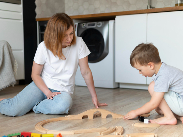 Young Boy Playing With Train With Mum