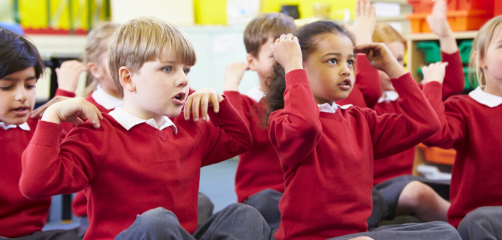 Children in classroom sitting and singing songs with actions
