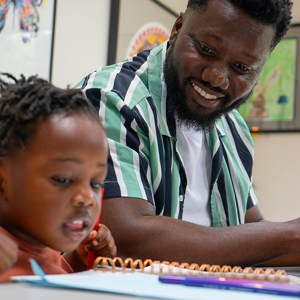 Young child and adult sitting down looking at a notebook